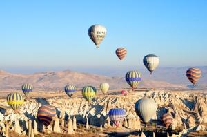 a bunch of hot air balloons flying in the sky at Old Greek House in Urgup