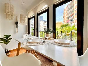 a dining room with a white table with chairs and windows at La Palmera Suite Calpe in Calpe