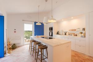 a kitchen with white cabinets and bar stools at Monte da Torre in Tavira