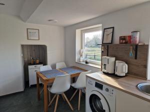a kitchen with a table and a washing machine at Rettiner Sandbank in Neustadt in Holstein