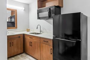 a kitchen with a black refrigerator and a sink at HomeTowne Studios by Red Roof Florence, KY-Cincinnati Airport in Florence