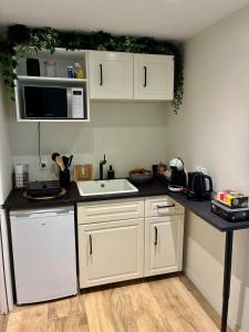 a kitchen with white cabinets and a white sink at Studio indépdendant dans un parc verdoyant avec piscine in Andrézieux-Bouthéon