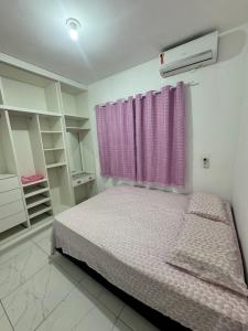 a bedroom with a bed with a pink curtain at Diamond Summer in Caucaia