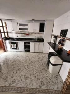 a kitchen with white cabinets and a counter top at Roomii Hostel in Villa de Leyva