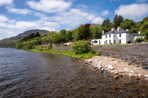 a white house on the shore of a river at Kylemore House in Kylemore