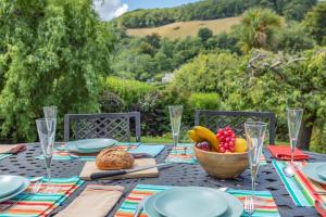 a table with plates and a bowl of fruit on it at 3 Bed in Berrynarbor oc-courtc in Berrynarbor