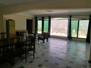 a dining room with a table and chairs and windows at Basera Lodges in Nathia Gali