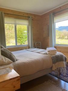 a bedroom with a large bed with two windows at Vuelta al Sur in Puelo