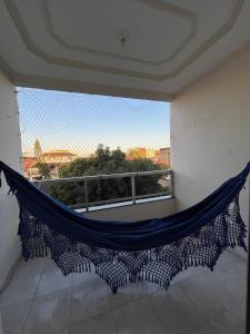 a hammock in a room with a large window at Apê 250m da Orla de Piúma in Piúma