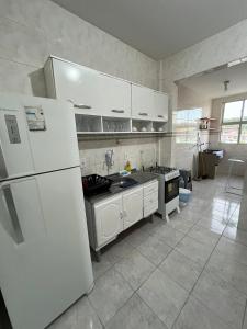 a kitchen with white appliances and a white refrigerator at Apê 250m da Orla de Piúma in Piúma