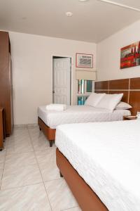 two beds in a room with white walls at Hotel Benidorm Panama in Panama City