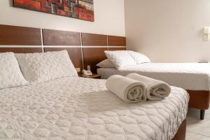 a hotel room with two beds with towels on the bed at Hotel Benidorm Panama in Panama City