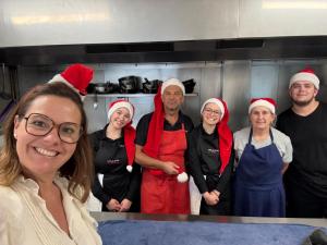 a group of people wearing santa hats in a kitchen at Les 3 rois by YY in Villers-Bocage