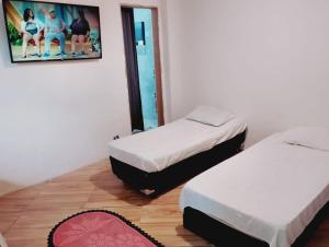 two beds in a room with a picture on the wall at pousada benção in Aparecida