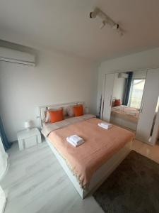 a white bedroom with a large bed with orange pillows at Otopeni Studio C2 3 Airport Therme in Otopeni