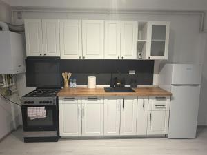 a kitchen with white cabinets and a wooden counter top at Otopeni Studio C2 3 Airport Therme in Otopeni