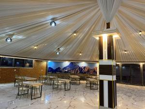 a dining room with tables and chairs and a ceiling at Skylight Wadi Rum Camp in Disah