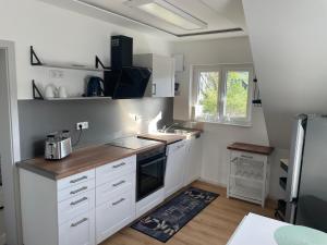 a kitchen with white cabinets and a sink at Komfort-Fewo mit Infrarotsauna & WLAN nahe Sorpesee - Haus am Krähenbach - Steinert in Sundern