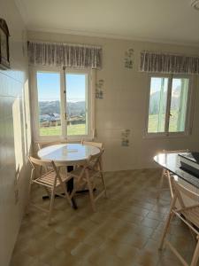a kitchen with a table and chairs and windows at Villa Laxes in Burela de Cabo