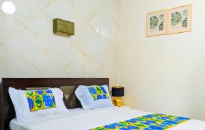 a bedroom with a bed with white sheets and colorful pillows at Appart M'Rode Baguida in Lomé +36 photos