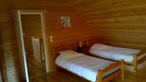 two beds in a log cabin with a doorway at Le Chalet de Seb in Ingouville
