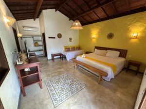 a bedroom with a bed and a couch and a table at Vila Sol Chalés in Pôrto de Pedras +65 photos