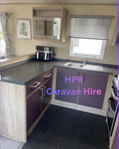 a small kitchen with a microwave and a sink at 3 bedroom, 2 bathroom caravan Presthaven Beach Resort in Talacre +9 photos