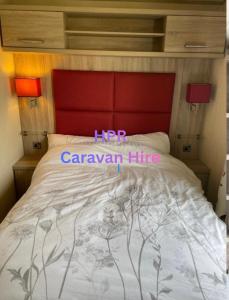 a bedroom with a bed with a red head board at 3 bedroom, 2 bathroom caravan Presthaven Beach Resort in Talacre