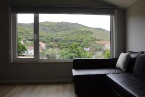 a living room with a couch and a large window at EiraDouro - Casa Oliveira in Mós +16 photos