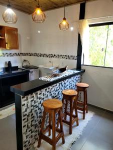 a kitchen with two bar stools and a counter top at Vila Mukaú in Porto Seguro +25 photos