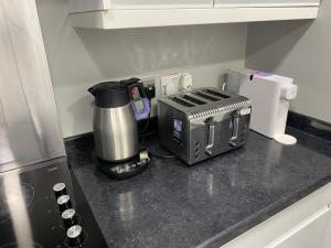 a kitchen counter with a coffee maker and a toaster at Marvel Abbeywood, Luxury 3 bedroom House with parking, 2mins walk to Elizabeth Line in Abbey Wood