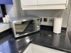 a microwave oven sitting on top of a kitchen counter at Marvel Abbeywood, Luxury 3 bedroom House with parking, 2mins walk to Elizabeth Line in Abbey Wood +24 photos
