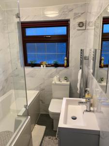 a bathroom with a sink and a toilet and a bath tub at Marvel Abbeywood, Luxury 3 bedroom House with parking, 2mins walk to Elizabeth Line in Abbey Wood