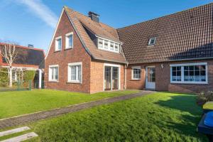 a large brick house with a grass yard at Ferienhaus Nordsee2 in Dornum
