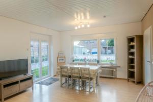 a dining room with a table and chairs and a tv at Ferienhaus Nordsee2 in Dornum