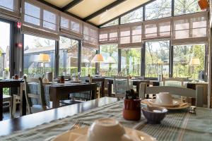 a restaurant with tables and chairs and windows at Hotel Le Beau Séjour in Nassogne