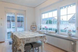 a dining room with a table and windows at Ferienhaus Nordsee2 in Dornum
