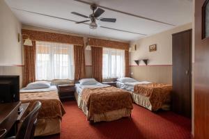 a hotel room with two beds and a ceiling fan at Pensjonat Stańczyk in Krakow