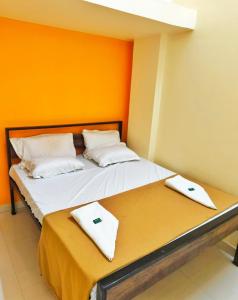 two beds in a room with orange walls at Shaktipeeth Yatrinivas in Kolhapur