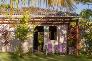 a small white house with purple chairs in the yard at Casa Aroeira Massarandupió in Entre Rios