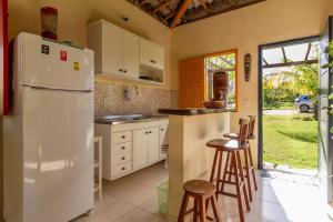 a kitchen with a white refrigerator and some stools at Casa Aroeira Massarandupió in Entre Rios +28 photos