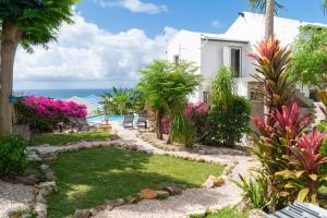 a house with a garden and the ocean in the background at Blue Sail Rooms in Koolbaai +48 photos
