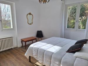 a bedroom with a bed and a chair and two windows at Le Jardin d'Elise - Maison 10 personnes avec jardin - proche centre ville in Brive-la-Gaillarde