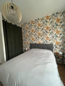 a bedroom with a white bed with a floral wallpaper at Appartement spacieux avec parking privé in Chalons en Champagne