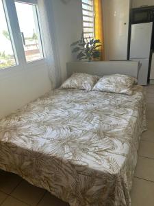 an unmade bed in a room with a window at Évasion Soleil in Le Gosier