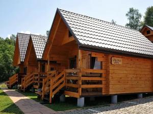 a wooden cabin with a porch and a sign on it at Domki Piękny Widok u Karola in Solina