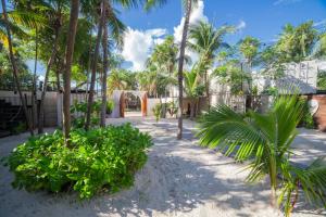 a courtyard with palm trees and a building at Alquimia Hotel Boutique in Tulum