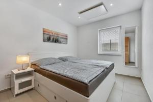 a white bedroom with a bed and a window at Apartment MINT in Senec +7 photos