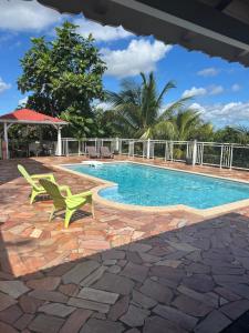 a swimming pool with two green chairs next to it at Le Papillon in Le Moule
