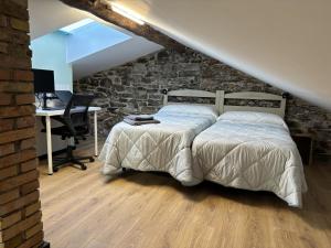 a bedroom with a bed with a stone wall and a desk at Ático en Jaca in Jaca